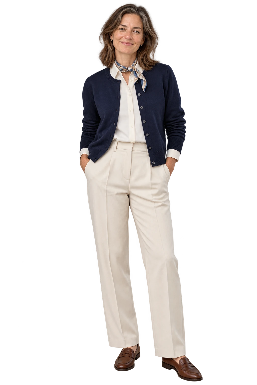 A woman wearing a navy cardigan over a cream shirt, cream pleated trousers and brown loafers